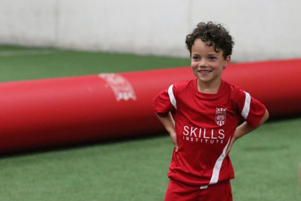 kid in red soccer jersey - skill institute